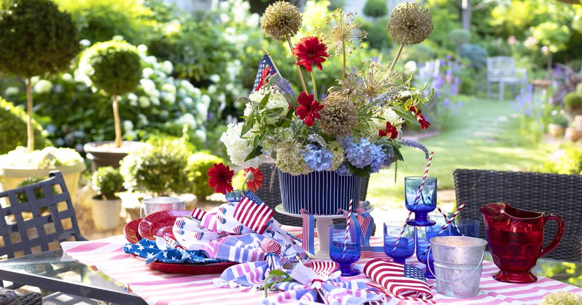 4th of July Tablescape includes a bouquet of Agapanthus and red blooms with a red checked tablecloth, red plates and blue drinkware