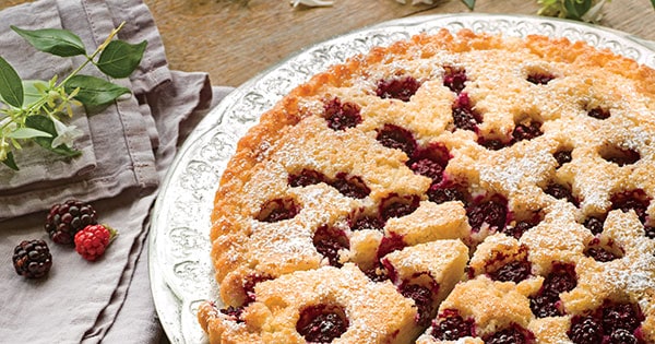 Blackberry almond tart on a plate with one slide cut
