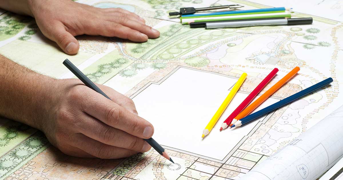 Hands holding colored pencil and sketching landscape plan for garden full of Southern Living plants