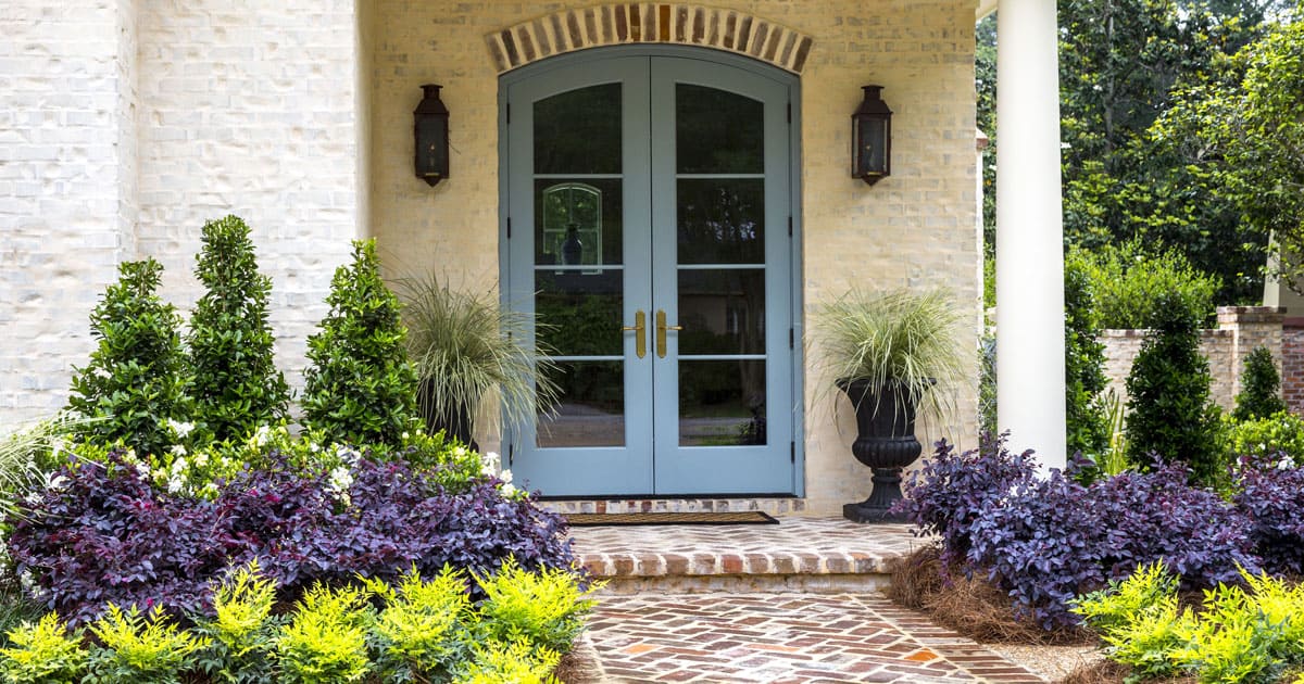 Symmetrical entryway garden beds made up of Oakland Holly in the back, Jubilation Gardenia in the middle and Red Diamond Loropetalum in the front