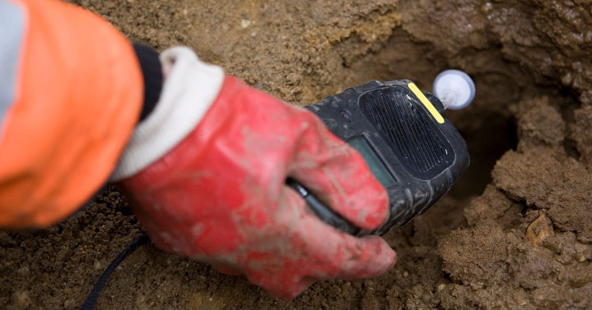 Red gloved hand holds electronic soil tester