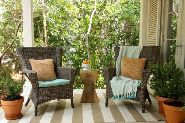 Frost proof gardenia in container on front porch with a two wicker chairs close up